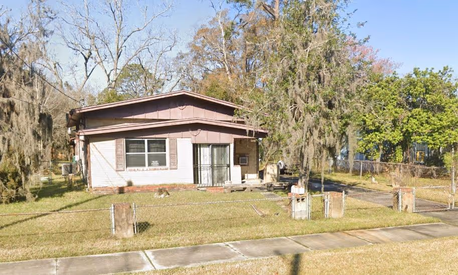 Single-story house with white exterior and black trim, a small front porch with stairs, landscaped front yard with grass and colorful plants.
